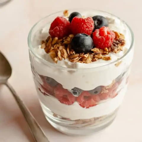 Breakfast Parfait with berries and granola sitting with elegant spoon