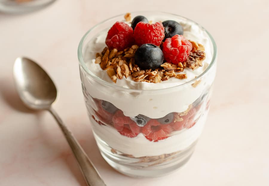 Breakfast Parfait with berries and granola sitting with elegant spoon