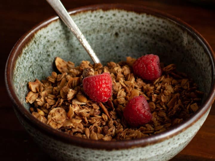 Granola in blue speckled pottery bowl with raspberries on top