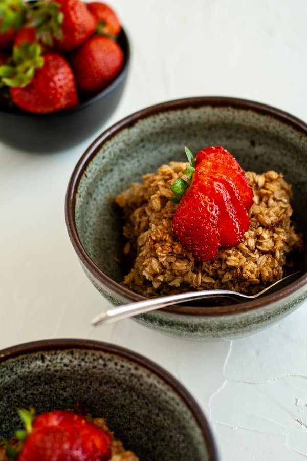 Baked oatmeal in a blue pottery bowl topped with a strawberry