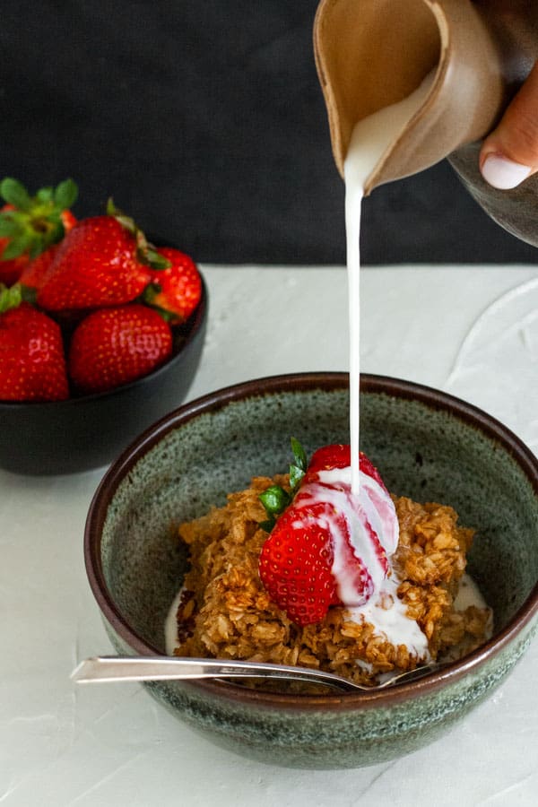 Baked Oatmeal topped with a strawberry and having milk poured onto it.