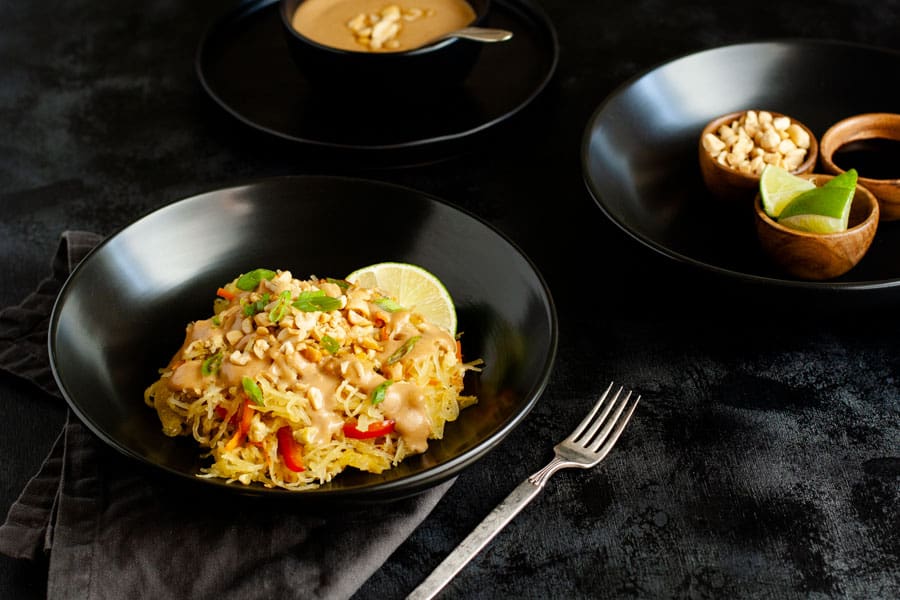 Spaghetti squash pad thai in black pasta bowl on black surface