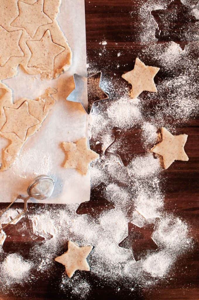 gluten free pecan shortbread cookies being cut out with star shapes surrounded by flour