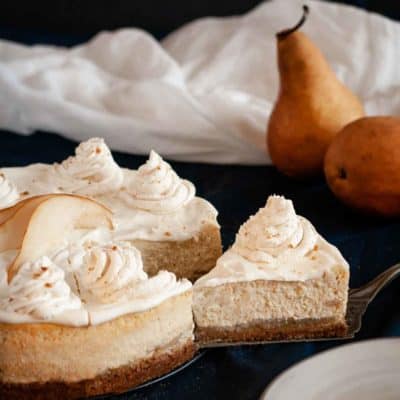 finished image of pear cheesecake with a slice of cheesecake being cut.