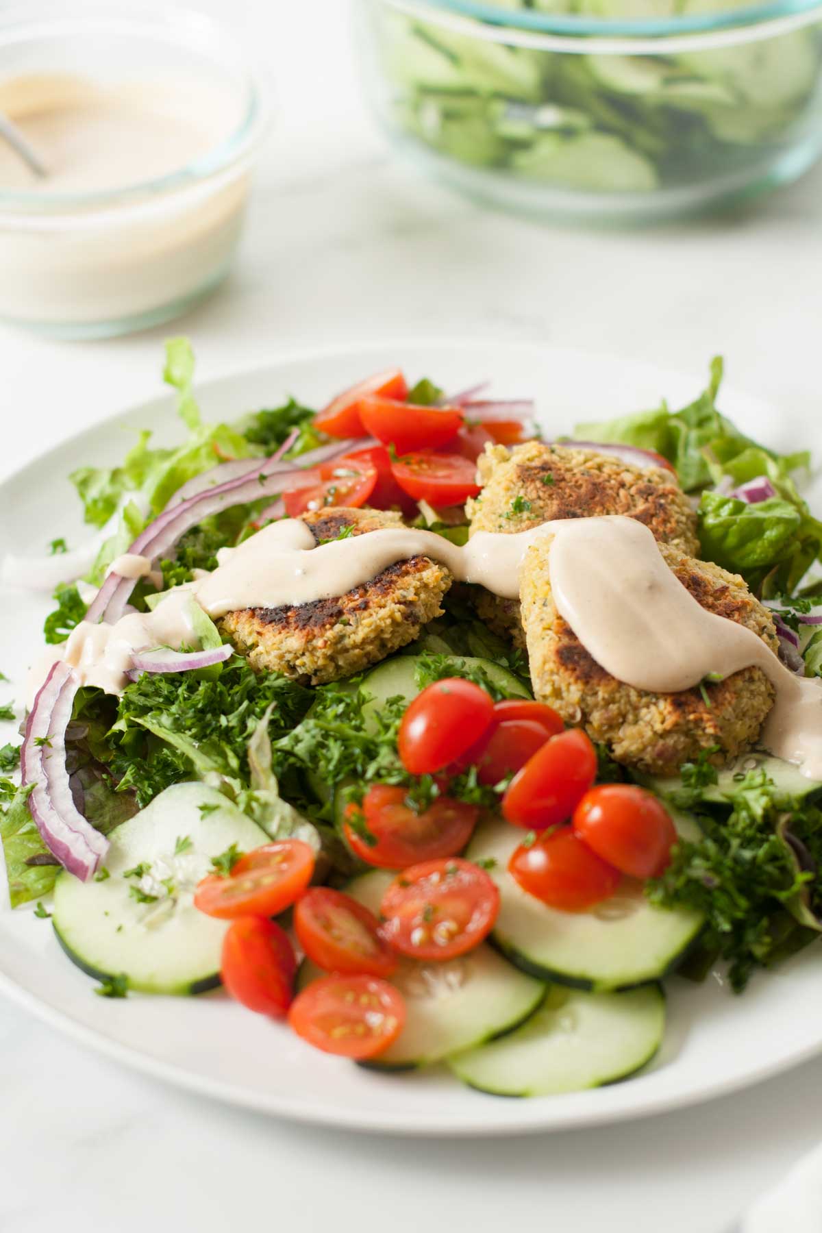 Falafel salad with tahini dressing finished dish served on white plate