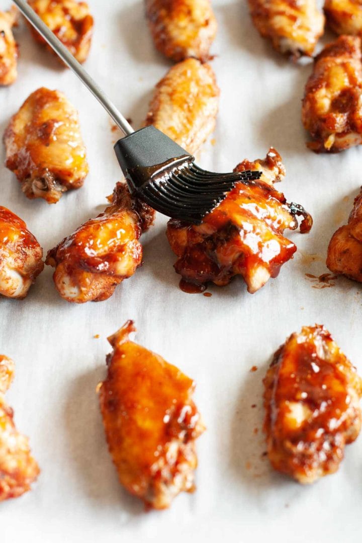 chicken wings being brushed with barbecue sauce