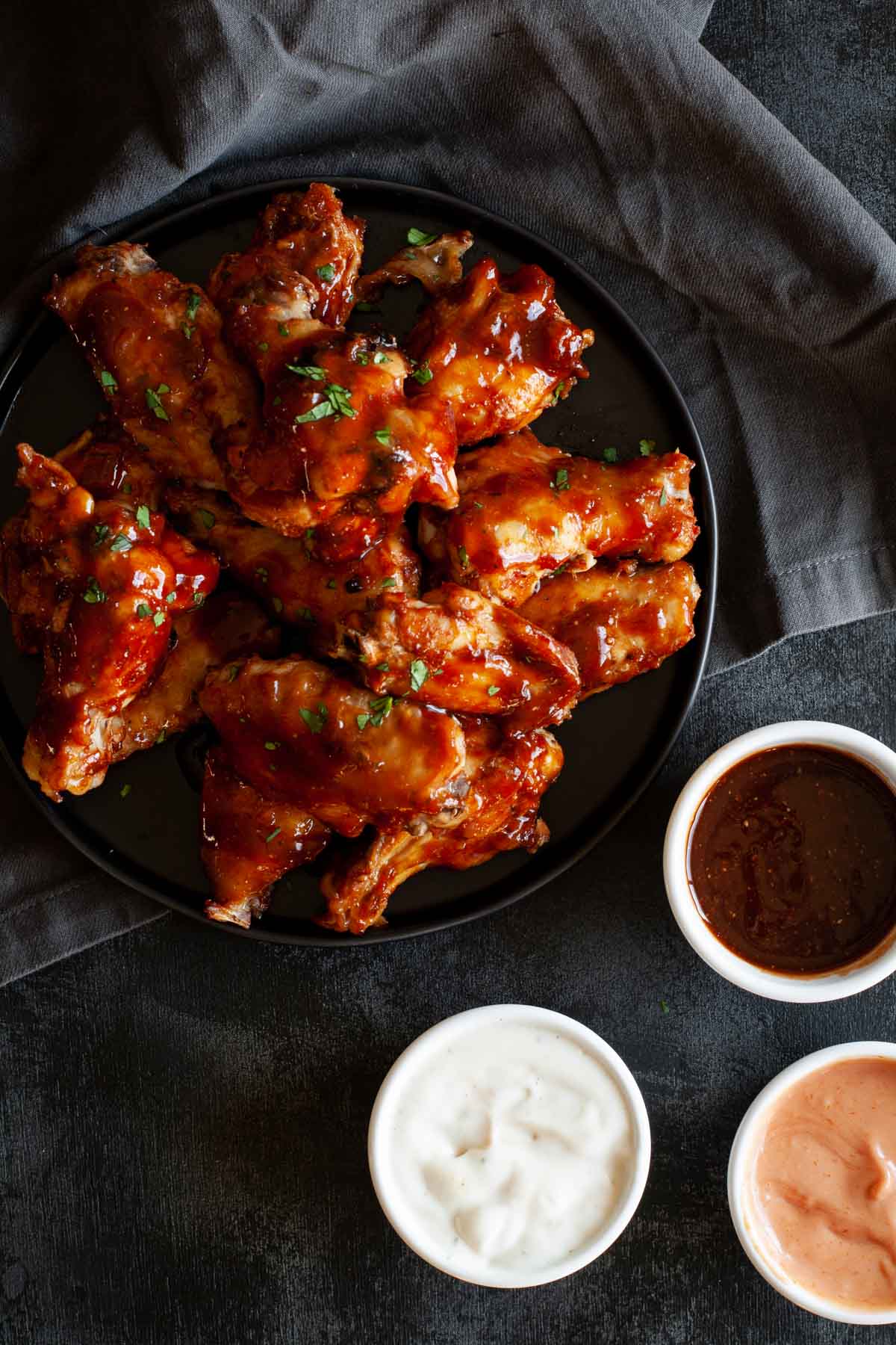 sweet and spicy chicken wings on a platter ready for serving, surrounded by multiple dipping sauces