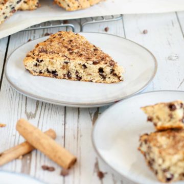 featured image for gluten free cinnamon scones, slice of scone displayed on a plate resting on a white wooden surface