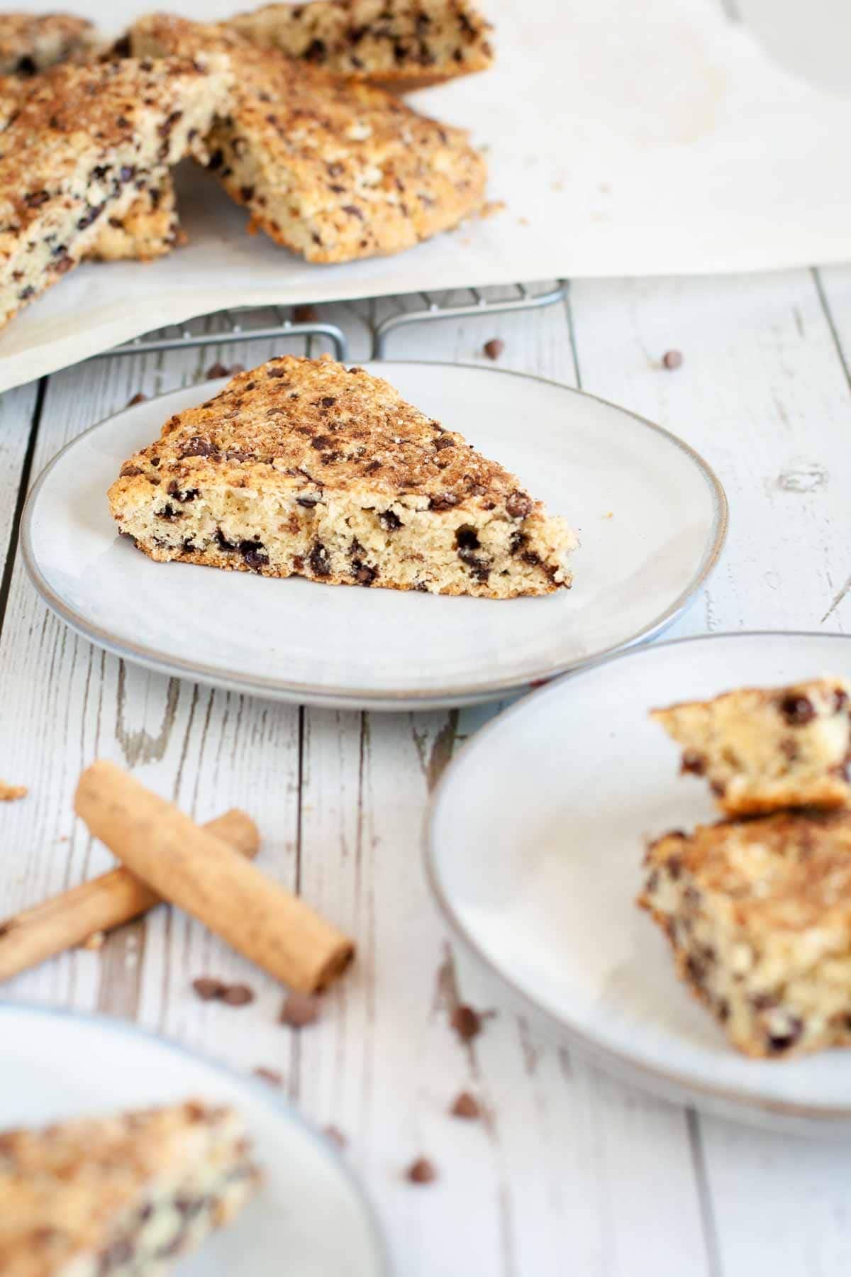 featured image for gluten free cinnamon scones, slice of scone displayed on a plate resting on a white wooden surface