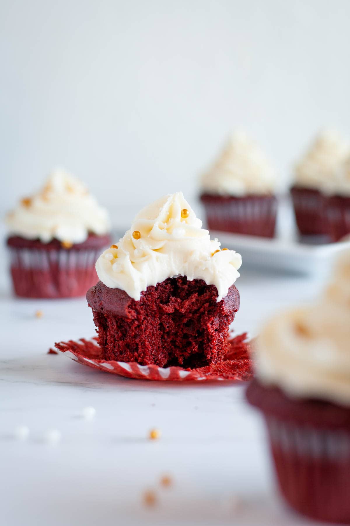 Featured image of a bite taken out of the gluten free red velvet cupcake with cream cheese frosting