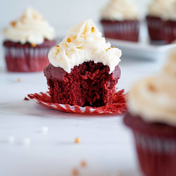 Recipe Card Image of a bite taken out of a ready to eat gluten free red velvet cupcake with cream cheese frosting