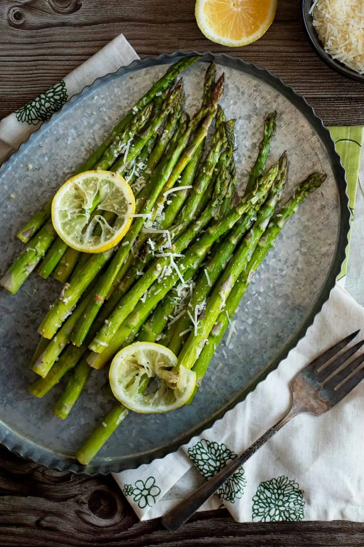 Roasted asparagus ready for serving on tin tray with parmesan and lemons