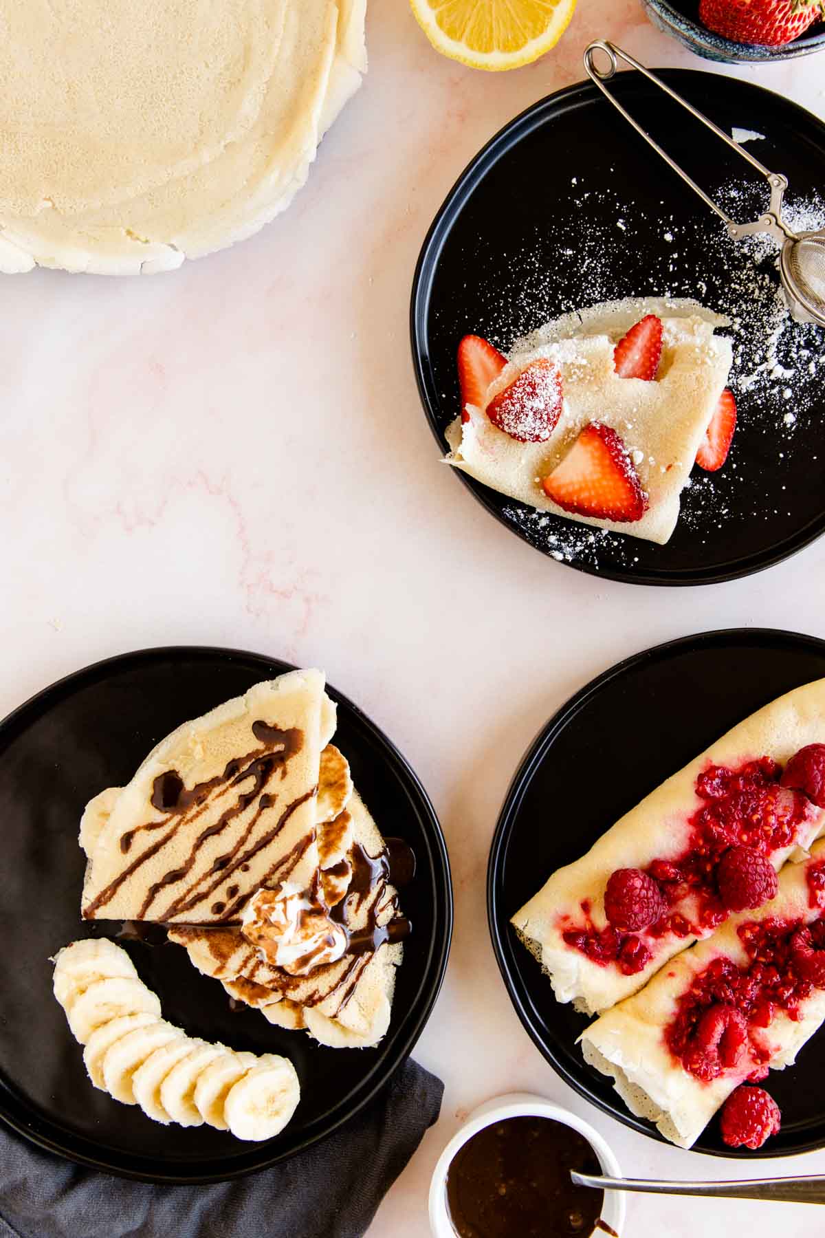 gluten free french crepes served with different toppings, like banana and chocolate suace, ricotta filling, or berries and powder sugar