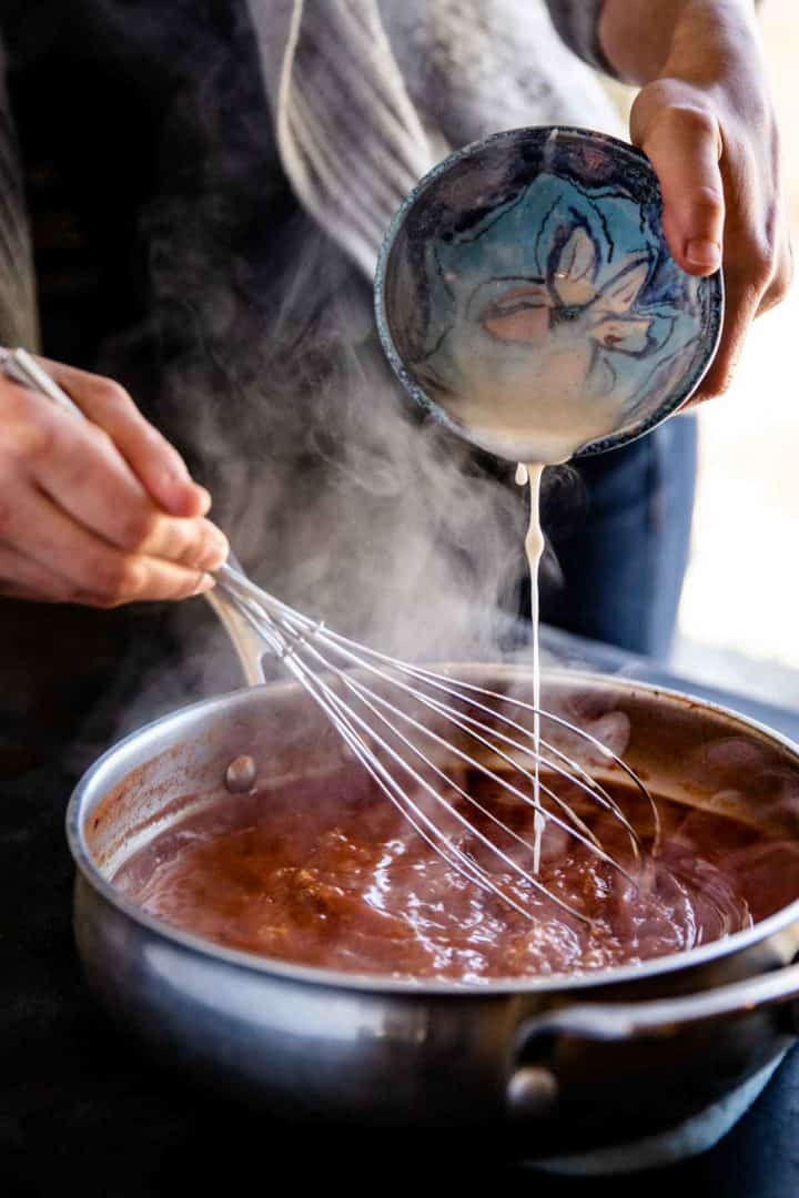 how to thicken the homemade Mexican enchilada sauce, whisking the flour blend into the boiling sauce.