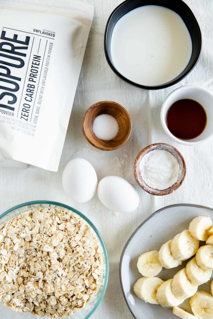 ingredients needed for flourless banana pancakes laid out in dishes displayed on a tablecloth