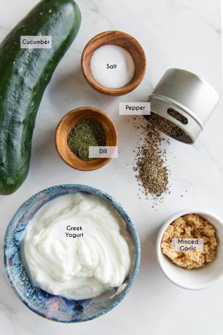 ingredients needed to make tzatziki sauce laid out on a marble surface ready to use