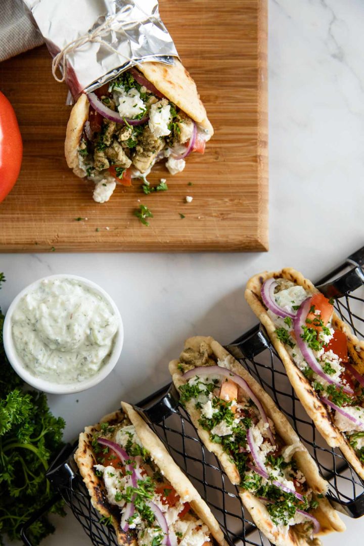 four chicken gyros displayed in a taco rack and ready to eat, surrounded by ingredients