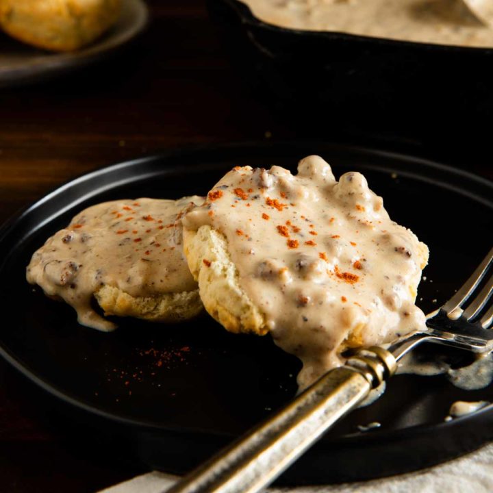 gluten free biscuits and gravy served on a black plate with a sprinkle of paprika